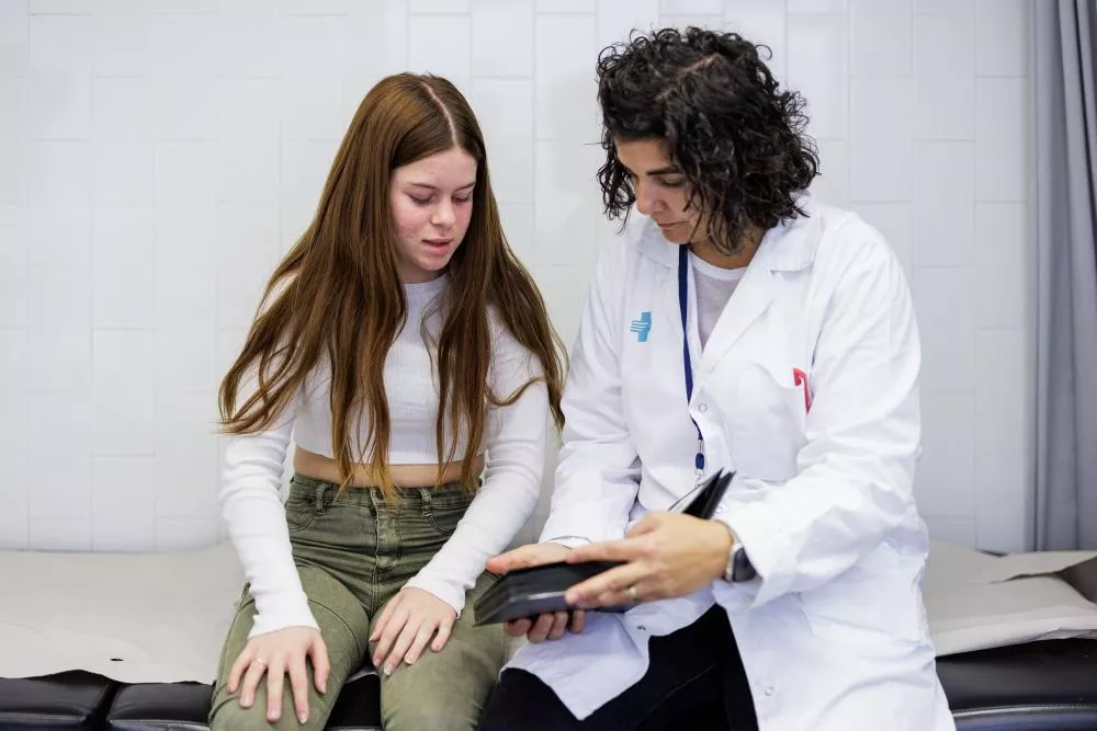 Médico enseñándole unos documentos a una paciente adolescente