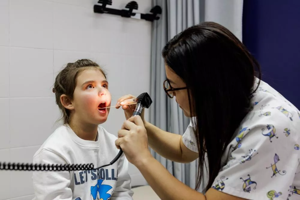 Médico observando la boca a una niña