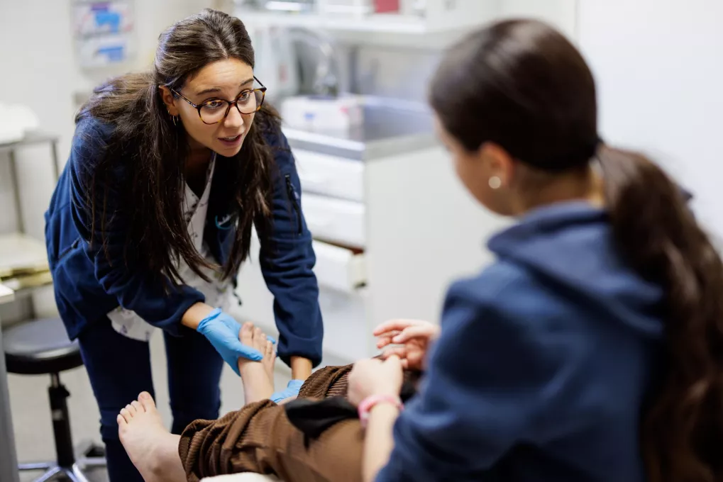 Médico mirando el pie de una chica adolescente