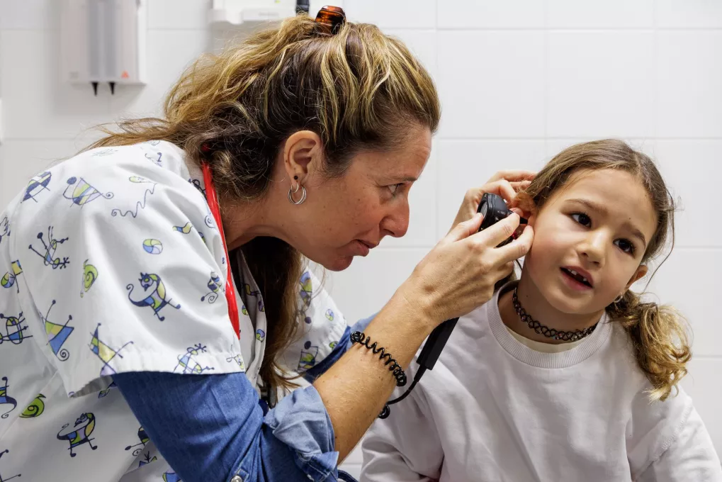 Médico observando los oídos de una niña