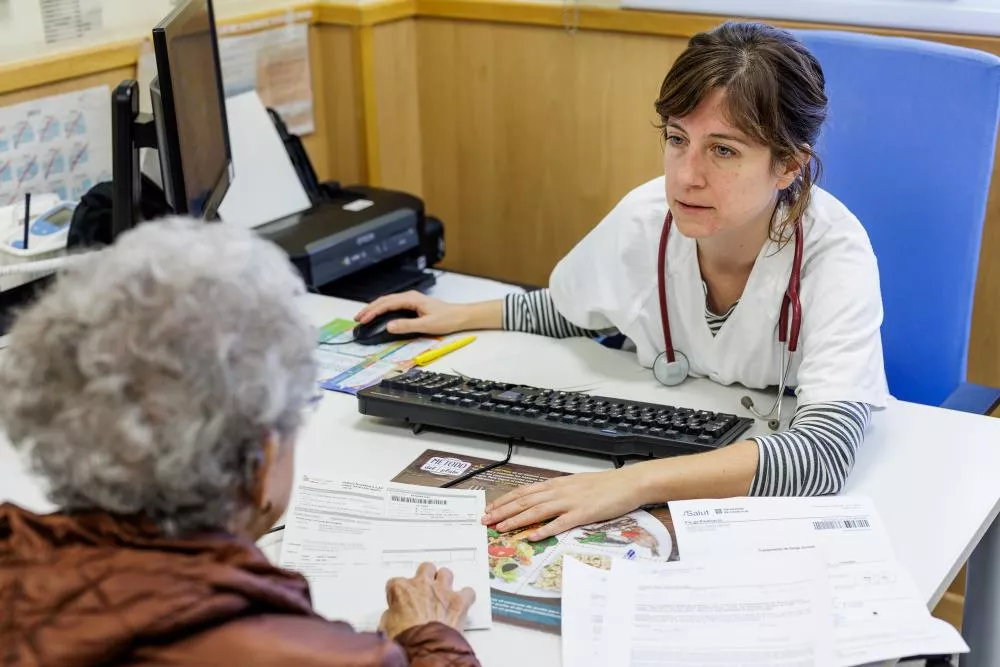 Una doctora parlant amb una pacient a la consulta.