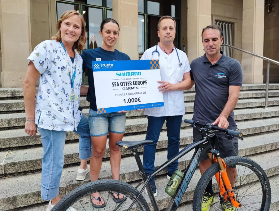 El director de Sea Otter Europe i la ciclista Txell Figueras, a l'entrada del Trueta per visitar el centre i fer el donatiu al Servei de Pediatria.