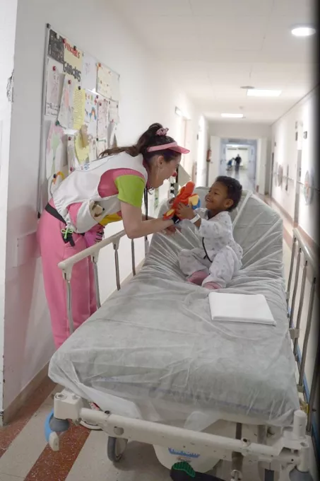 Pallassos hospitalaris de Pallapupas comparteixen activitats lúdiques amb un infant.