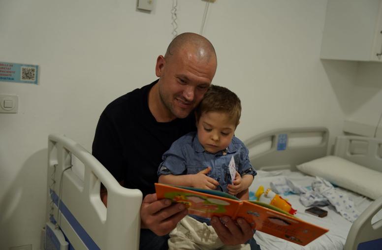 Un pacient pediàtric i un familiar fullegen un llibre en el marc de la celebració de Sant Jordi 2026 al Trueta.