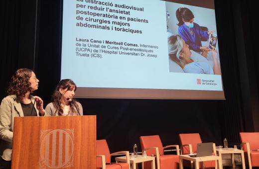Les infermeres Laura Cano i Meritxell Comas exposen el seu estudi sobre la reducció de l'ansietat postoperatòria mitjançant distracció audiovisual i musical durant la jornada d'experiència del pacient.