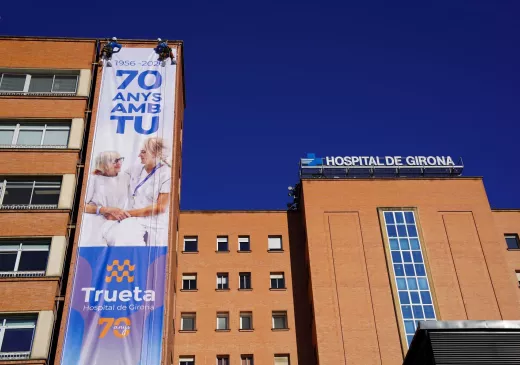 Operaris instal·len a la façana de l'Hospital Trueta la lona commemorativa del 70è aniversari del centre