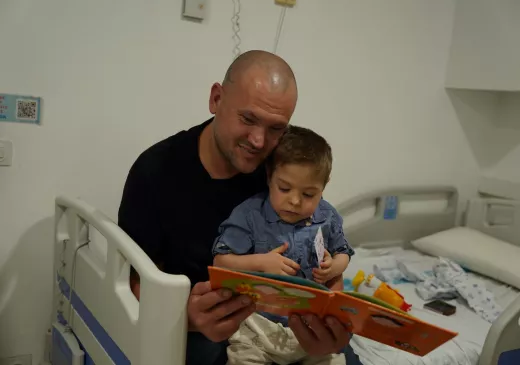 Un pacient pediàtric i un familiar fullegen un llibre en el marc de la celebració de Sant Jordi 2026 al Trueta.